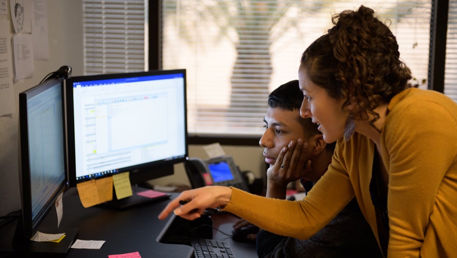 advisor assisting a student with a desktop