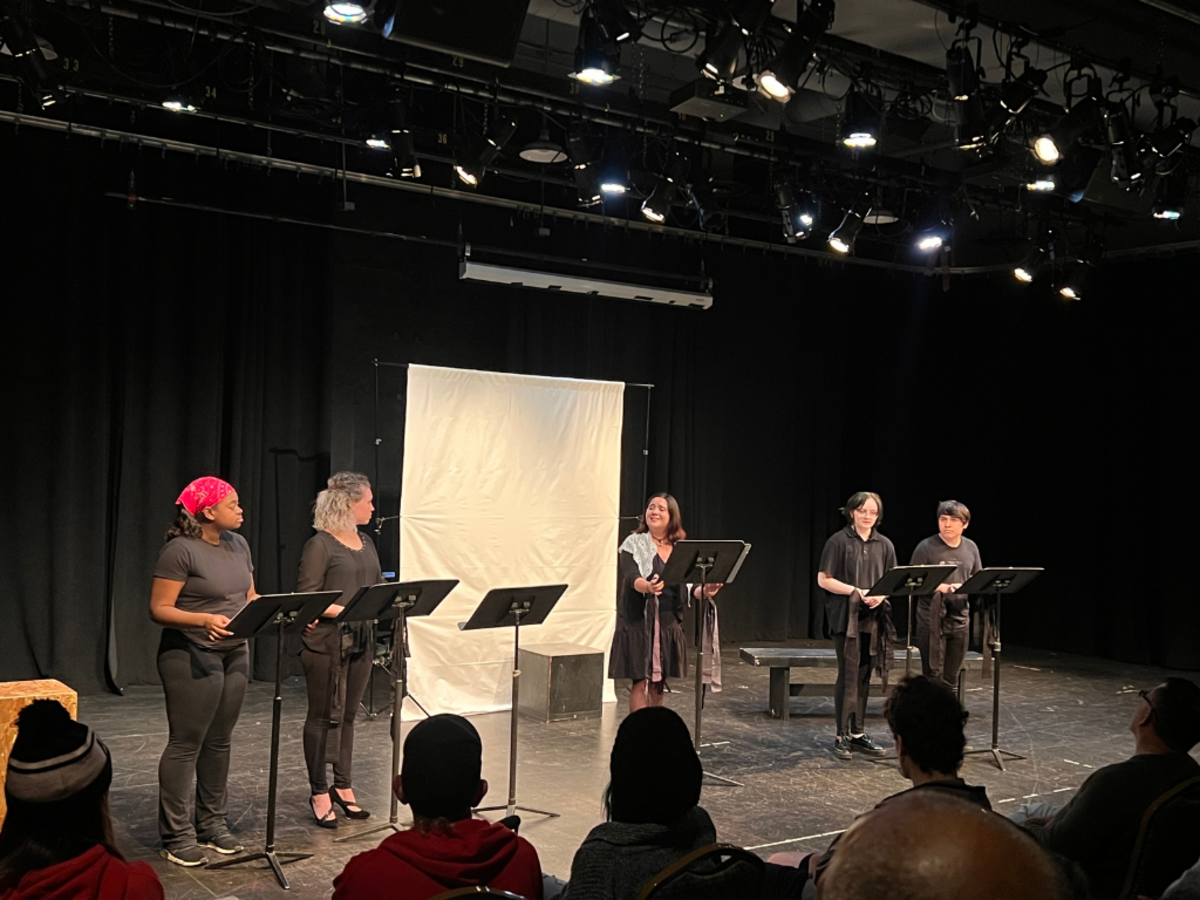 Actors participate in a staged reading in a black box theatre