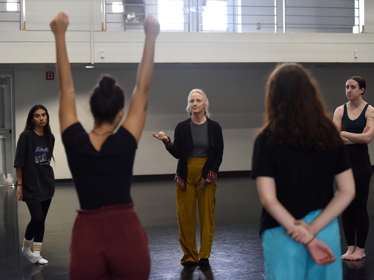 An instructor teaches inside a light-filled dance studio