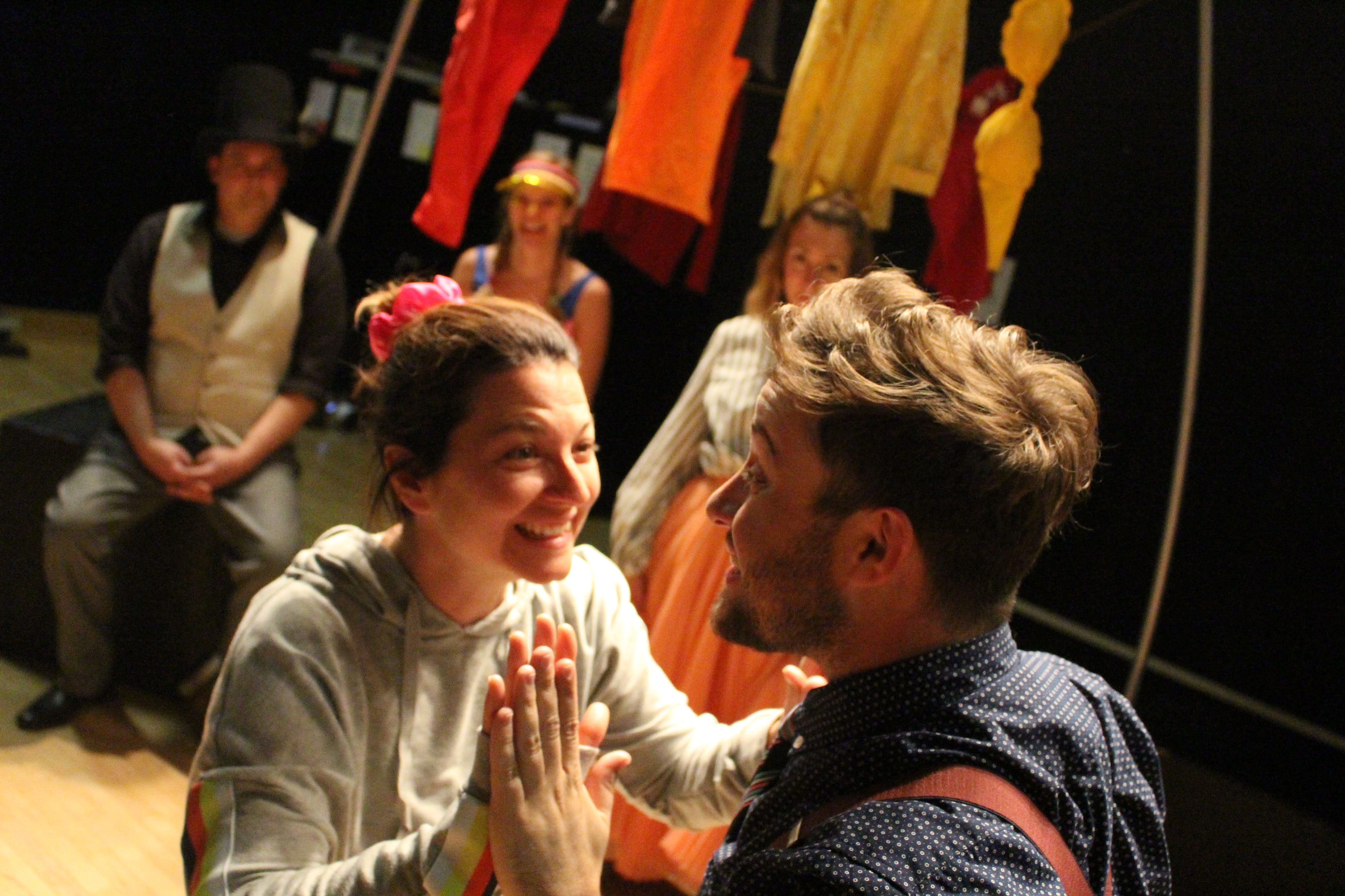 Two people stand in front of each other, hands together and smiling